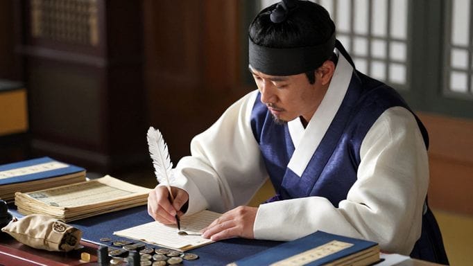 고서적과 엽전이 놓인 책상 위에서 펜으로 통장 내역을 꼼꼼히 정리하는 노비의 모습. 옆에는 작은 엽전 자루가 놓여 있다.